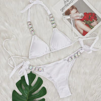 Bikini brésilien à strass effet diamant brillant blanc à plat sur une fourrure blanche, feuille verte et magazine