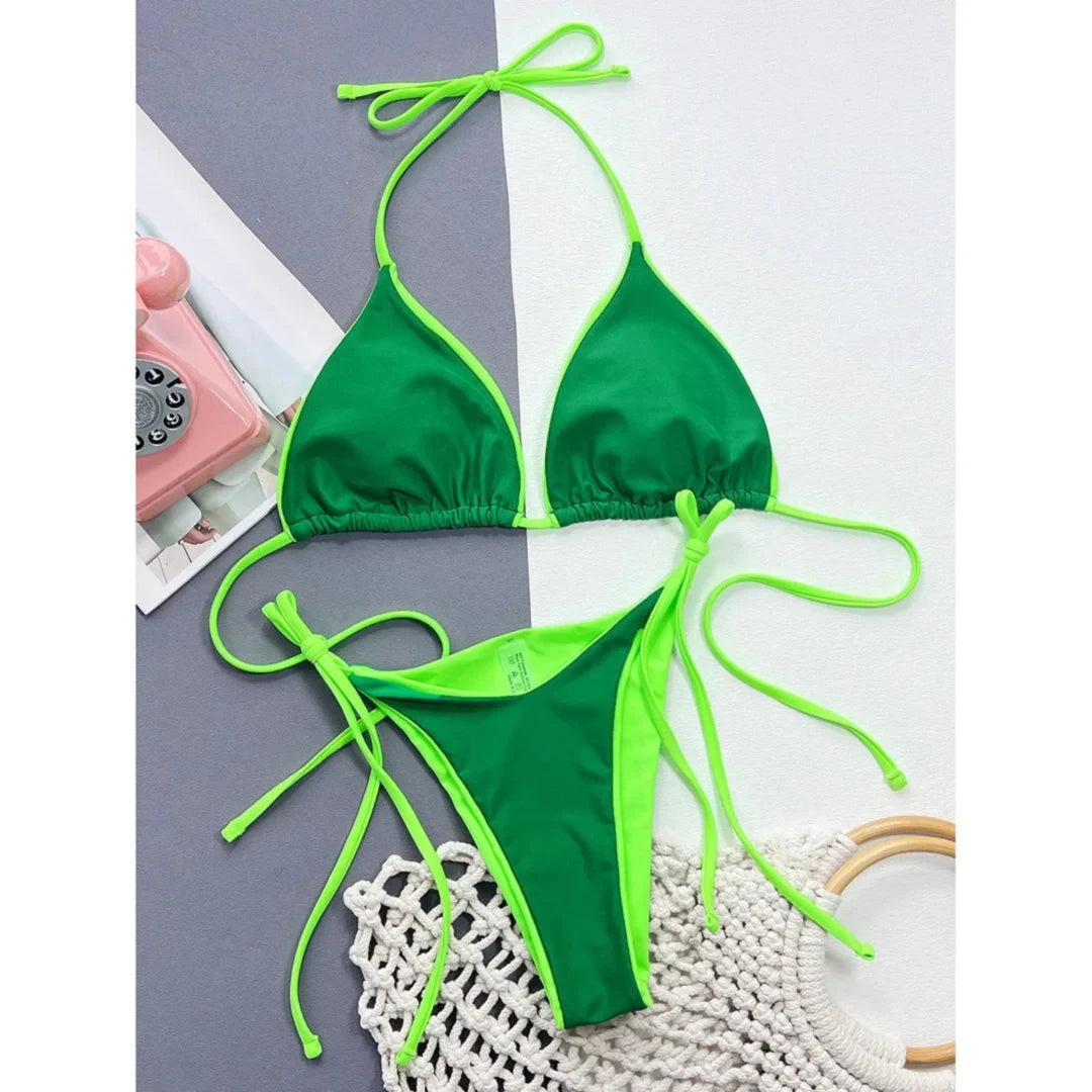Bikini brésilien col halter taille basse vert foncé posé à plat avec téléphone rétro rose, liens verts fluo sur les côtés