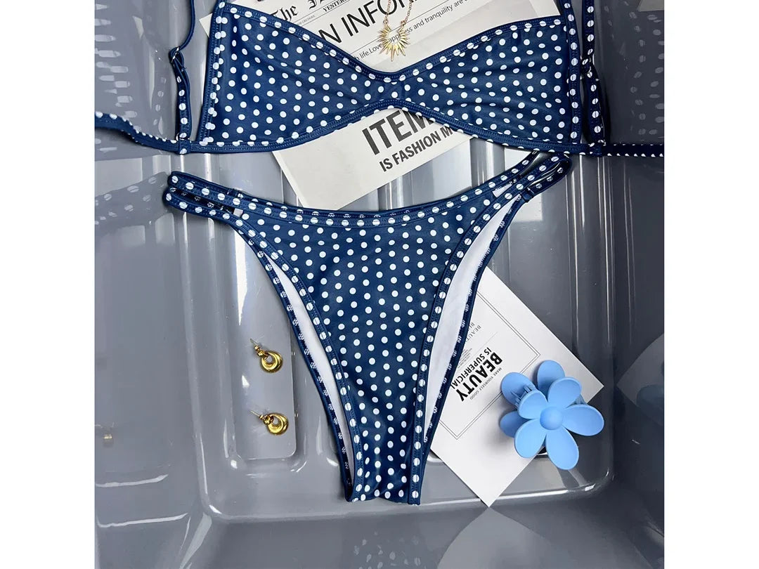 Bikini bralette taille basse bleu marine à pois blancs et bretelles fines, posé à plat dans un bac transparent