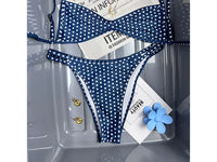 Bikini bralette taille basse bleu marine à pois blancs et bretelles fines, posé à plat dans un bac transparent