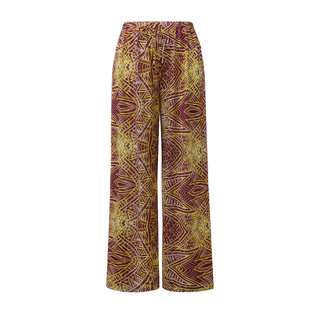 Gros plan sur les motifs ornementaux jaunes et violets du pantalon large, taille élastique à lien, posé à plat