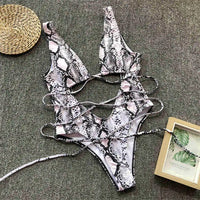 Monokini décolleté plongeant découpe ventre imprimé blanc posé à plat sur tapis, lanières croisées et découpe centrale