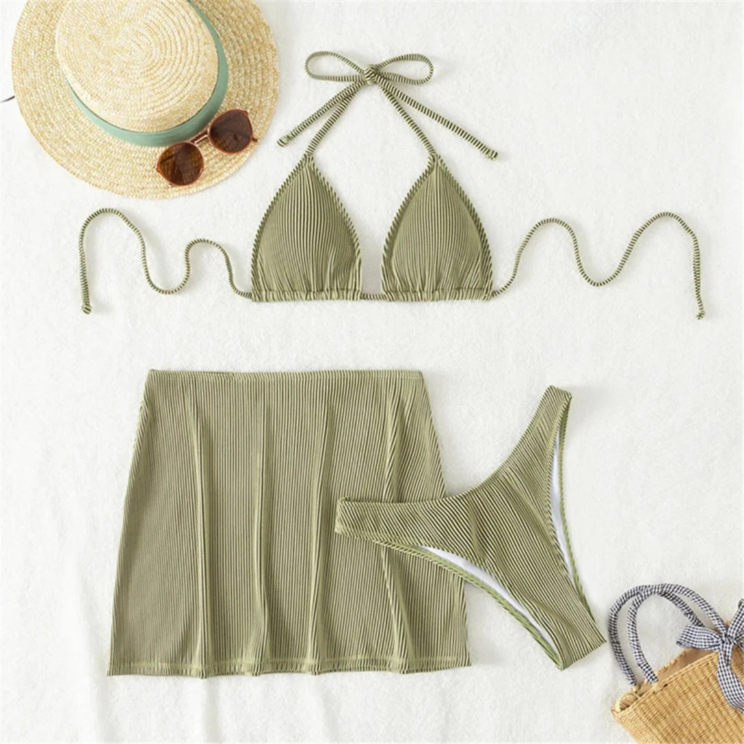 Maillot trois pièces côtelé tour de cou avec jupe vert olive posé à plat, chapeau de paille et lunettes de soleil