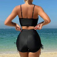 Bikini taille haute short froissé noir vu de dos, bretelles fines et lacets latéraux du short sur la hanche, en bord de mer