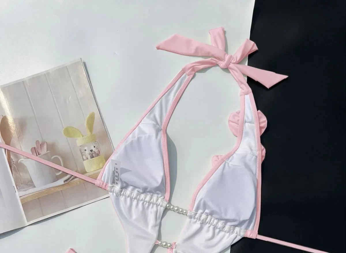 Gros plan sur le haut du maillot une pièce décolleté plongeant fleurs 3D rose poudré
