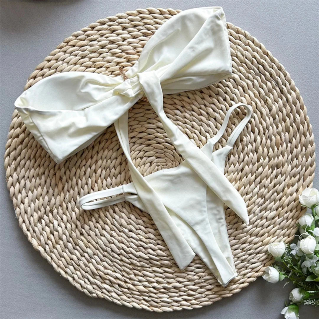 Bikini bandeau string échancré à étoile métallique beige déployé à plat, haut noué en nœud volumineux et slip string