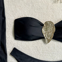 Gros plan sur le haut bandeau noir et l'anneau métallique doré ciselé, bas noir visible sur fond blanc texturé