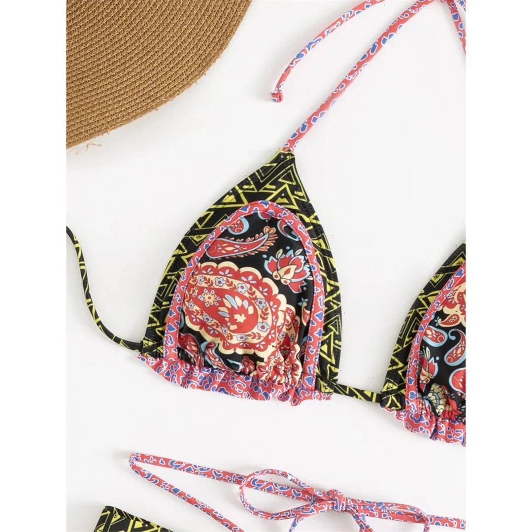 Gros plan sur le haut imprimé noir à motifs paisley rouges, bordure rose et volants, vue rapprochée du triangle