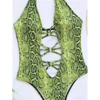 Gros plan sur les lacets croisés et les découpes du monokini imprimé serpent vert, en plan rapproché
