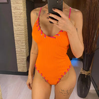 Maillot de bain une pièce côtelé orange porté de face, mains sur les hanches, bordures lacées fuchsia au col v
