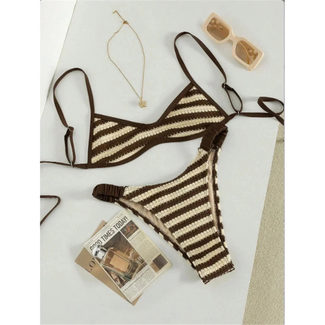 Bikini crochet triangle rayé marron et crème posé à plat sur une table, bas échancré et fines lanières, lunettes