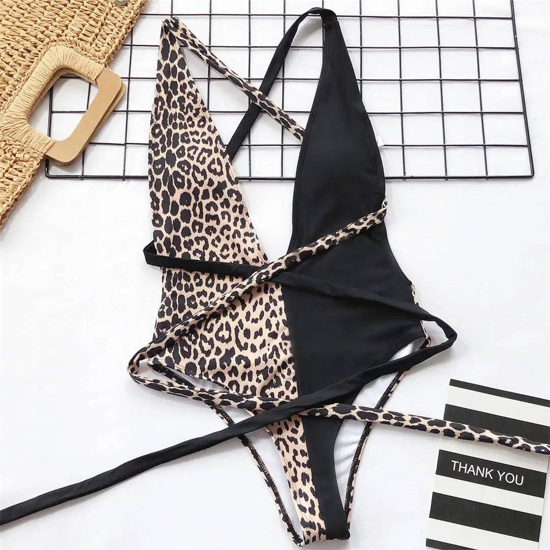 Maillot de bain une pièce triangle croisé imprimé léopard noir posé à plat, moitié léopard et moitié noire avec lanières