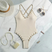 Maillot de bain une pièce côtelé beige posé à plat sur marbre avec accessoires de plage, bretelles croisées