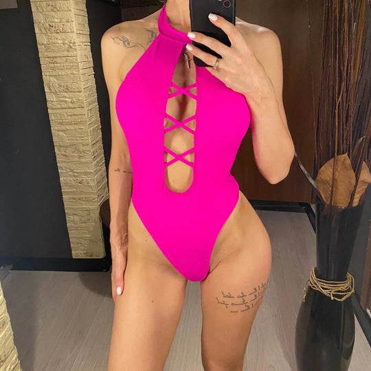 Maillot de bain une pièce col haut à lacets rose vif porté de face devant un miroir, décolleté ajouré en croisillons