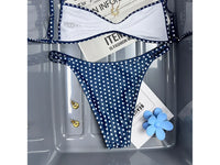 Bikini bralette taille basse bleu marine à pois blancs, bretelles fines, vu à plat avec lunettes de soleil