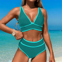 Bikini taille haute décolleté en V sans armatures bleu paon à liserés turquoise porté de face sur une plage