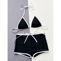 Bikini tour de cou noir à liseré blanc posé à plat sur fond bicolore, haut triangle et short à cordon blanc