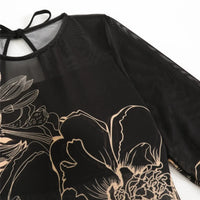 Gros plan sur l'épaule et la manche du body noir à fleurs au trait beige, encolure nouée d'un lien noir