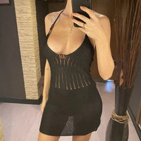 Robe de plage courte en crochet noire à col V, portée de face par une femme debout dans une pièce en bois