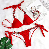 Bikini brésilien à strass effet diamant brillant rouge à plat sur une fourrure blanche, à côté d'un magazine