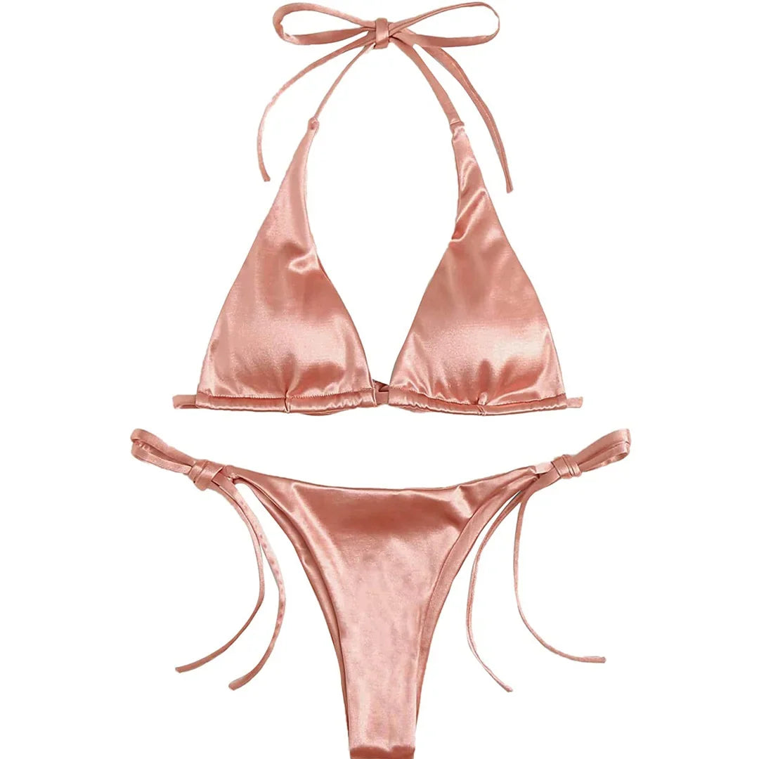Bikini brésilien satiné rose posé à plat sur fond blanc, haut triangle à bretelles de cou et bas à fins lacets