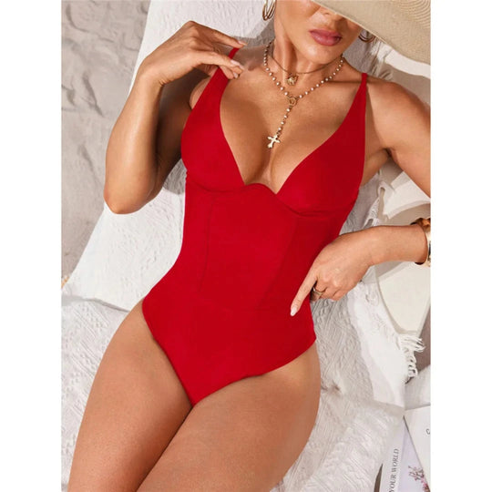 Maillot de bain une pièce gainant à lacets rouge porté de face assise sous un chapeau, buste structuré et bretelles