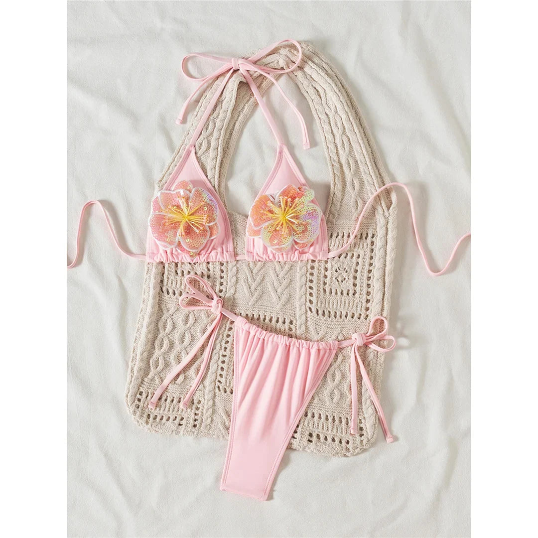 Bikini rose à fleurs en relief posé à plat sur un gilet en crochet beige, bas à nœuds sur les côtés