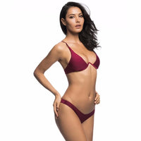 Bikini à armatures rembourré rouge bordeaux porté de profil sur fond uni clair, main posée sur la hanche