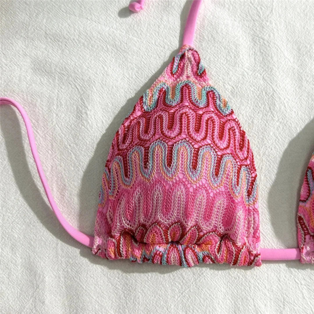 Gros plan sur le haut triangle rose vif au motif ondulé crocheté et sa fine lanière tenue au cou