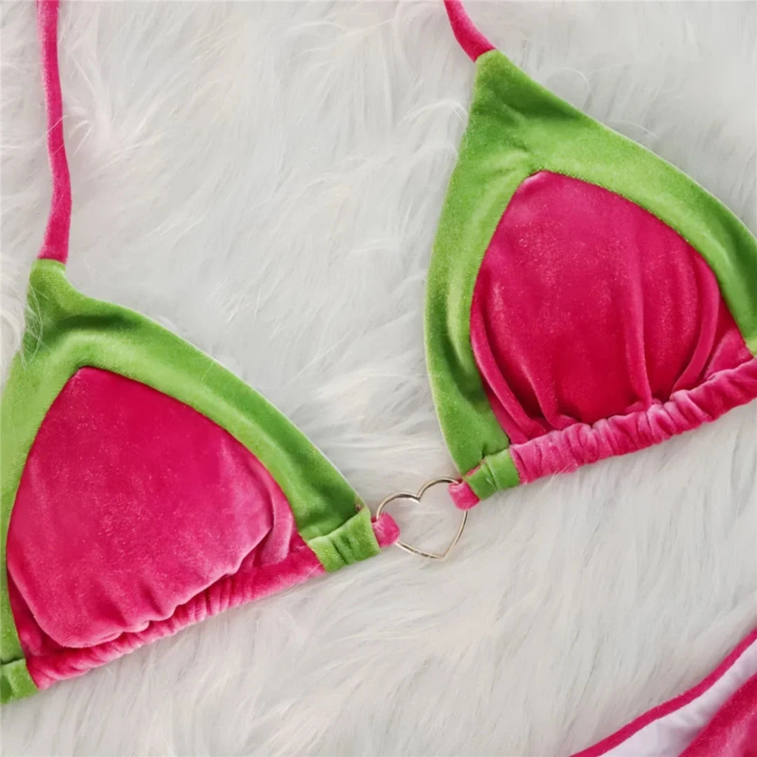 Gros plan sur les triangles en velours rose et bordure verte d'un bikini, anneau doré en forme de cœur