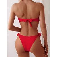 Bikini bandeau à fleurs en relief rouge vu de dos, nœud au centre du bandeau et fleurs fixées sur les côtés du bas