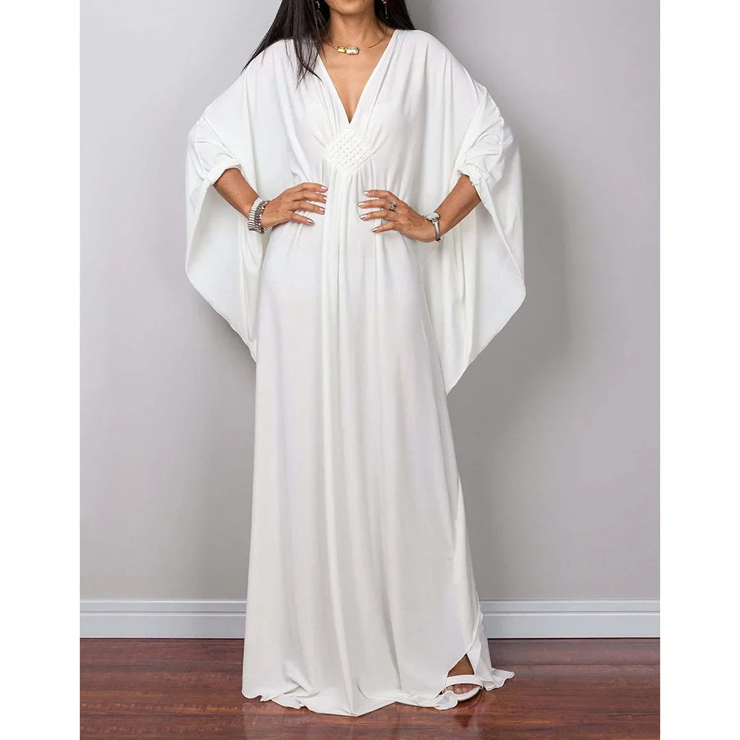 Robe de plage longue kaftan manches chauve-souris blanc portée de face, mains sur les hanches et col V tressé au buste