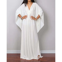 Robe de plage longue kaftan manches chauve-souris blanc portée de face, mains sur les hanches et col V tressé au buste