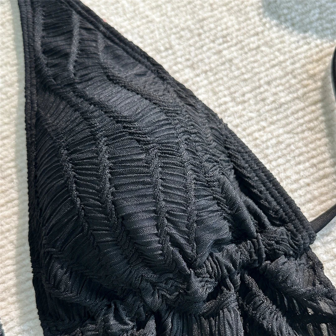 Gros plan sur le haut texturé du maillot de bain trois pièces noir, motif en relief et col halter