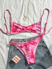 Bikini triangle échancré imprimé fleuri rose posé à plat sur un short en jean, grosses fleurs roses et bretelles fines
