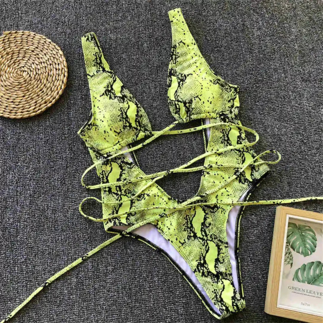 Monokini décolleté plongeant découpe ventre imprimé vert posé à plat sur tapis gris, lanières longues déployées