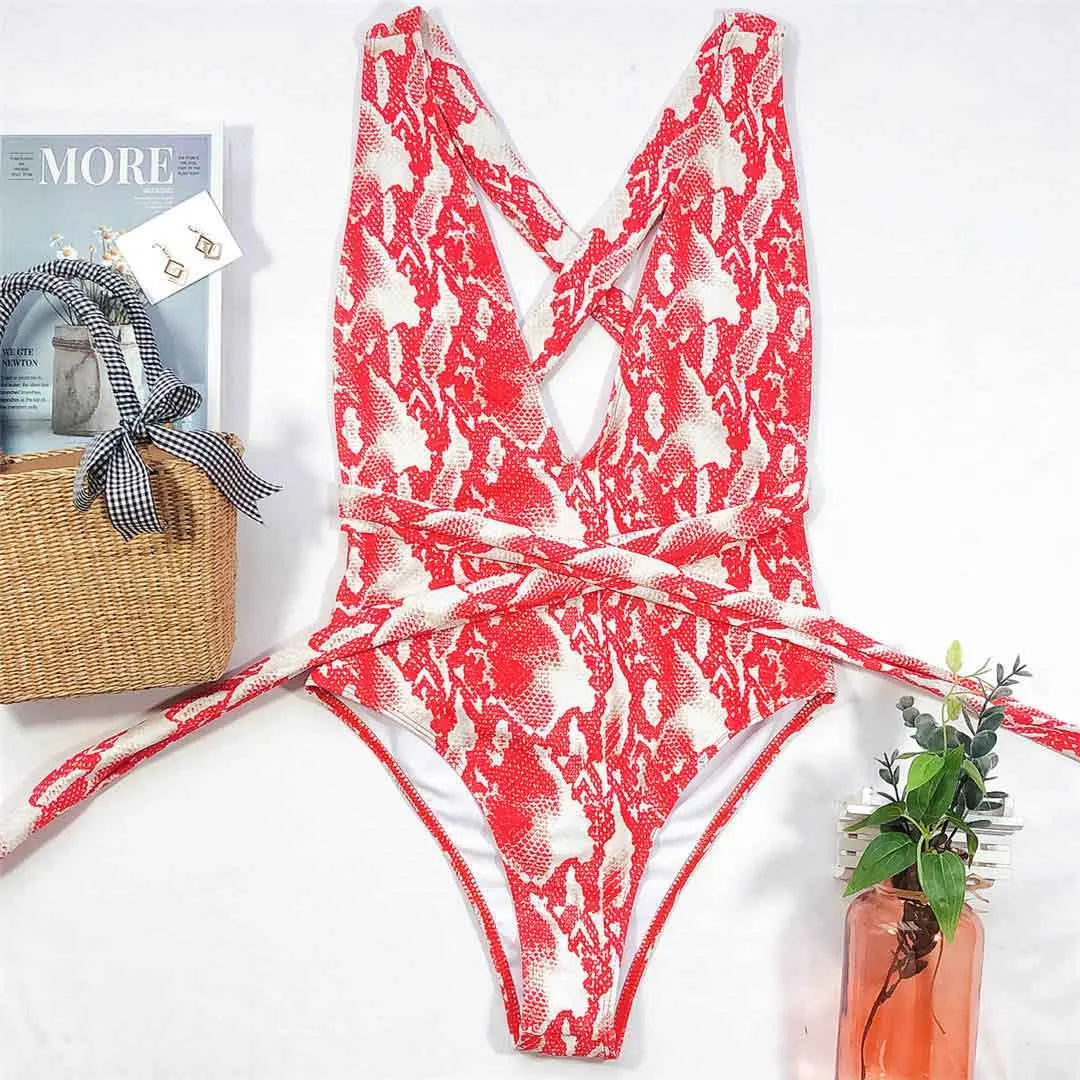 Maillot de bain une pièce triangle croisé imprimé serpent rouge posé à plat sur fond clair, bretelles croisées au dos