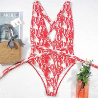 Maillot de bain une pièce triangle croisé imprimé serpent rouge posé à plat sur fond clair, bretelles croisées au dos