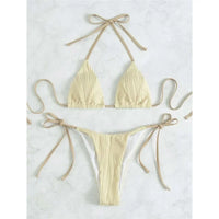Bikini brésilien tour de cou froncé texturé beige à plat sur du marbre blanc, lacets latéraux longs